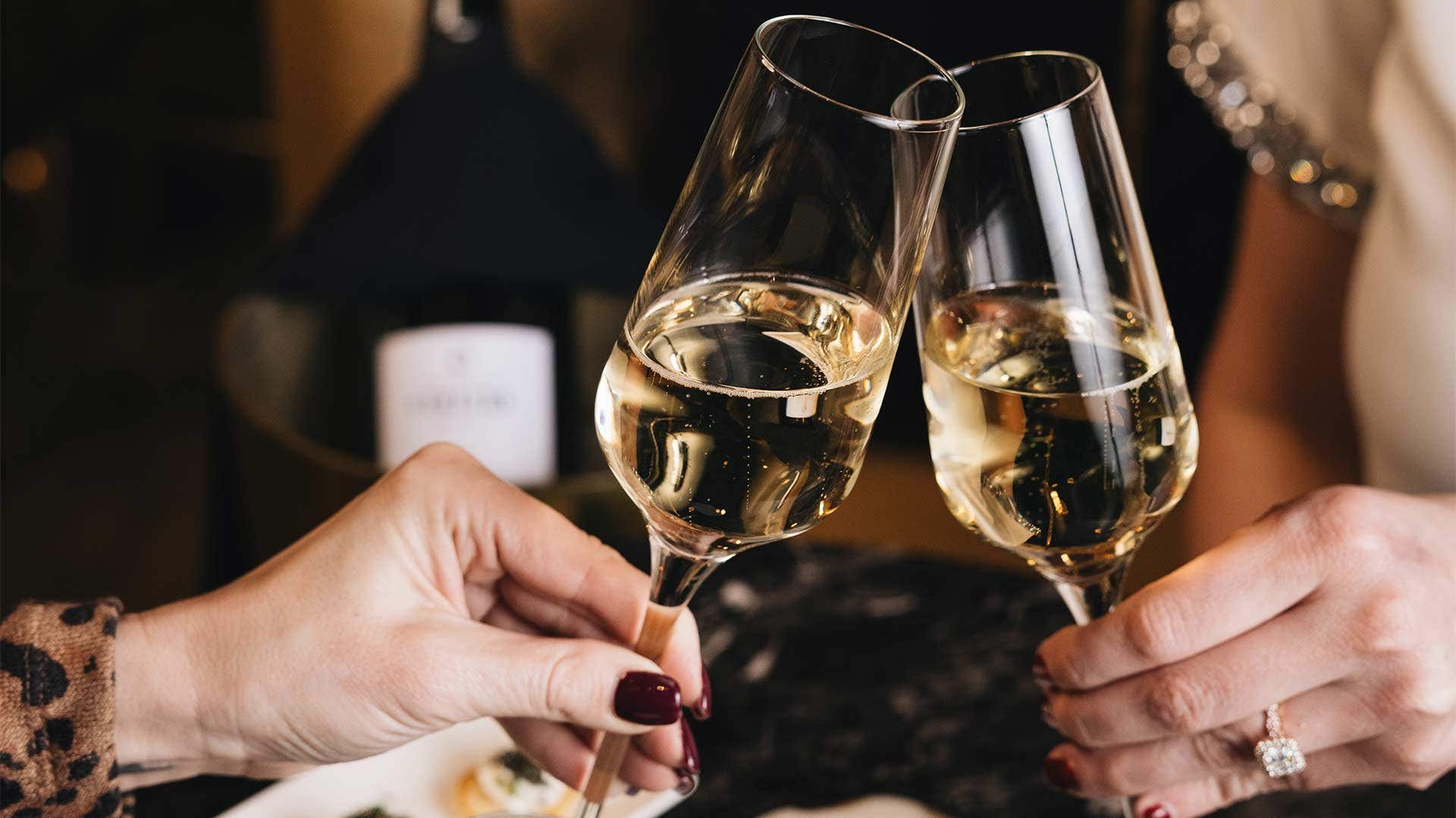 Two champagne flutes filled with sparkling wine toasting against each other